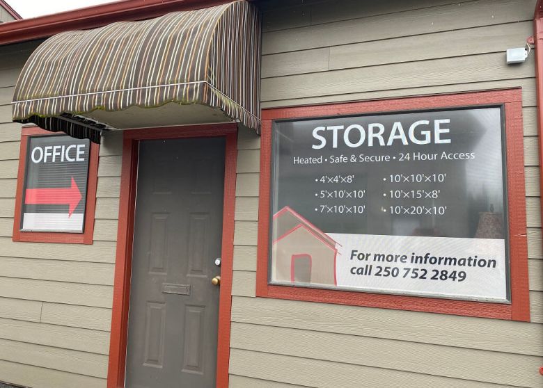 Front of PQ Self Storage building with gates and sign about first month free promo